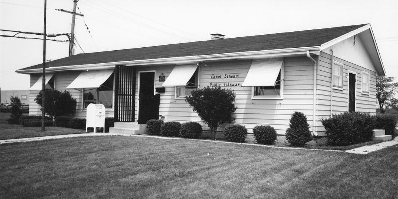 Black and white photo of small building with Carol Stream Public Library lettering outside entrance