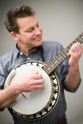 A photo of Jim Gill strumming his banjo