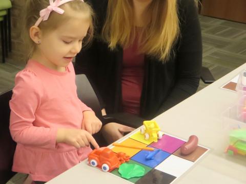 Child matching colored objects to colors on a colored mat.