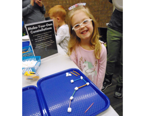 Smiling child with constellation craft made from marshmallows and toothpicks.