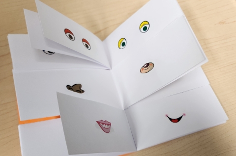 A blank book has been split into thirds, with silly eye, nose, and mouth stickers stuck on. Children can flip to different combinations.