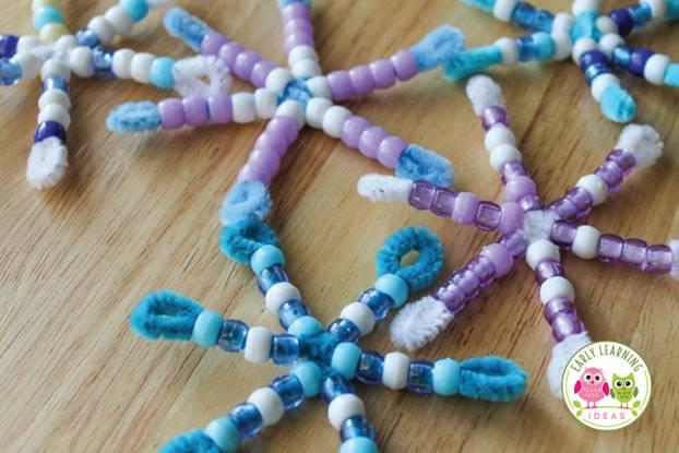 Various pipe cleaner and bead snowflake crafts on a table