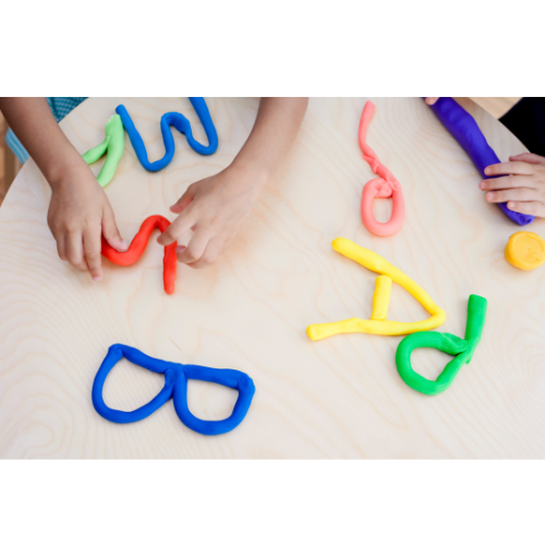 Children's hands making letters from Play-Doh.