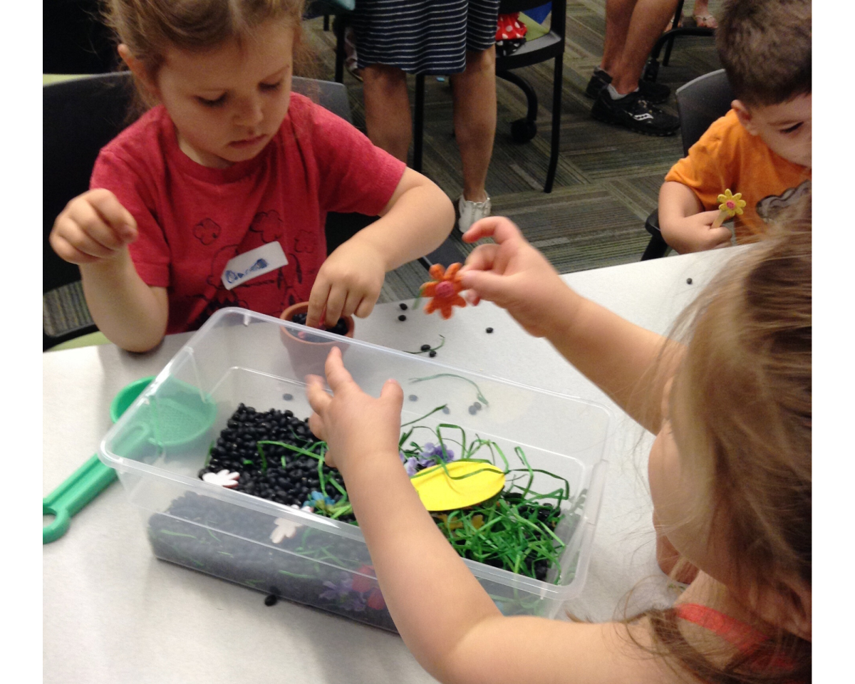 Two children playing with a garden-themed sensory bin.