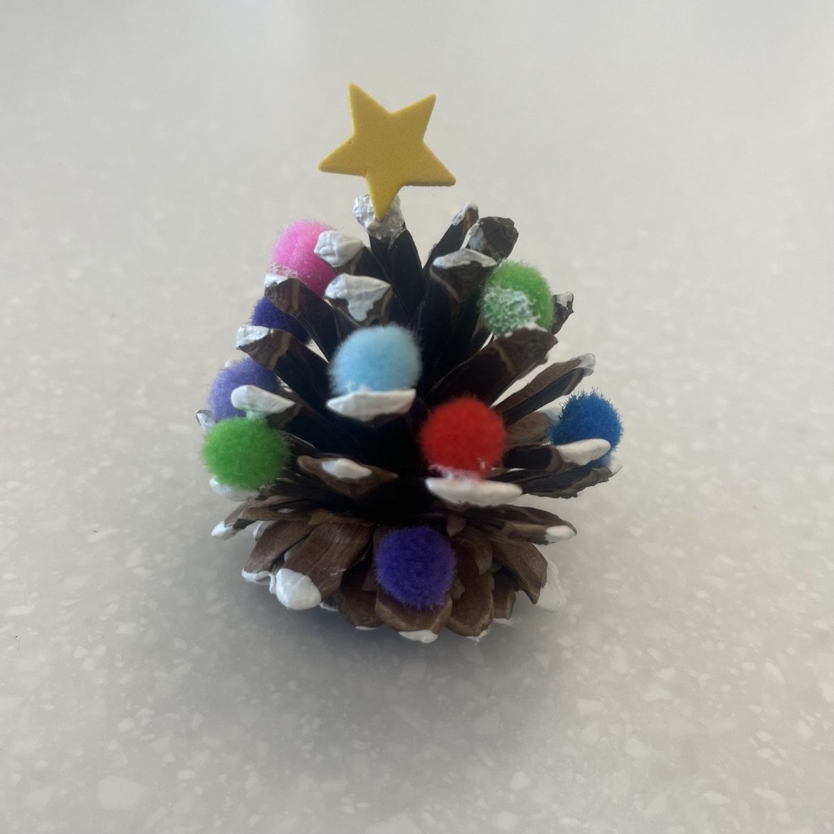 pinecone with small pom poms and white paint snow